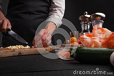 Chef slices garlic for cooking shrimp dishes. Culinary dish, recipe book, seafood Stock Photo