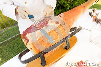 Chef slices raw ham Stock Photo