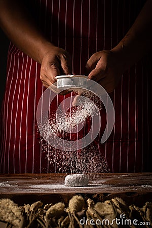 Chef spreading flour on bakery prepare for baking. Cook showing Stock Photo