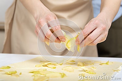 Chef spreads the apple slices on to the thinly rolled dough. Apple pie making process Stock Photo