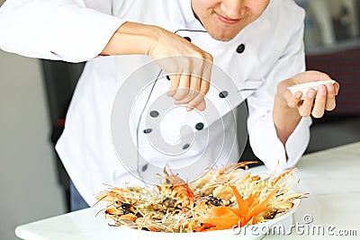 Chef sprinkling salt all over grilled prawns in the kitchen Stock Photo