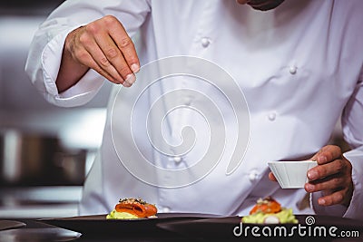 Chef sprinkling spices on dish Stock Photo