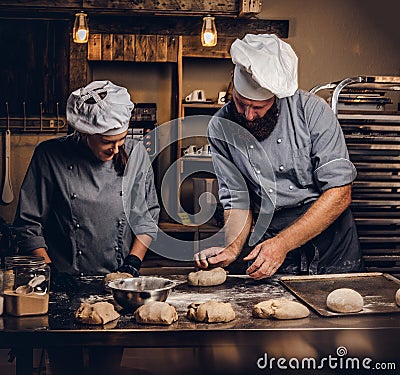 Chef teaching his assistant to bake the bread in a bakery. Stock Photo