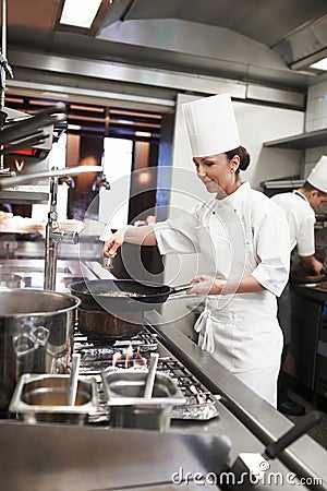 Chef, woman and frying pan with sauce in restaurant kitchen, catering service and prepare food for fine dining Stock Photo