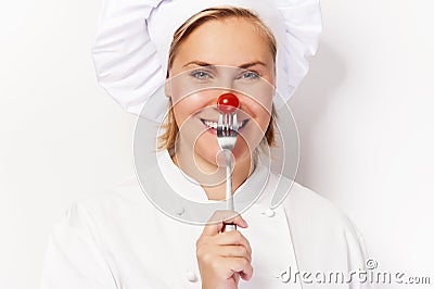 Chef woman holdinh a fork with tomato against her nose, standing Stock Photo