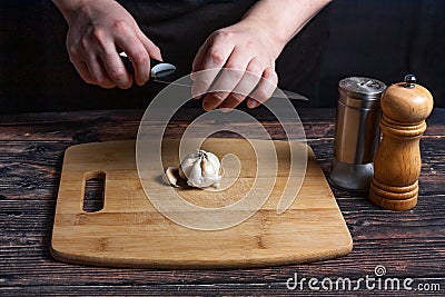 Chef at work. Cook`s hands are tearing a knife over garlic. Preparing the ingredients for the future dish. Stock Photo