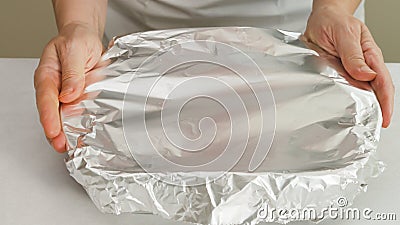 Chef wraps baking pan with aluminum foil. Stock Photo