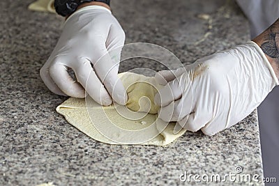 Chef wraps pizza ingredients in dough with his hands Stock Photo