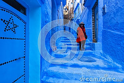 Asian woman tourist in red dress walking on a street in Medina of Chefchaouen Editorial Stock Photo