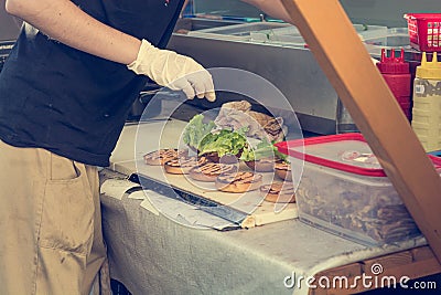 Cheff preparing delicious burgers - view from the side of food stand. Stock Photo