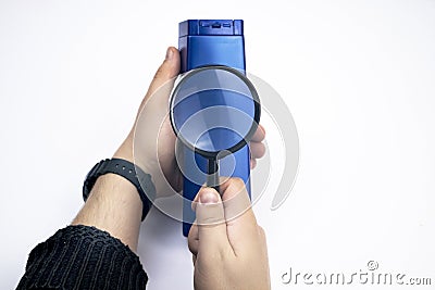 Chemical components on the shampoo label. A hand holds a blue jar and a magnifier, where the harmful ingredients of a detergent Stock Photo