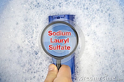 Chemical components on the shampoo label: Sodium Lauryl Sulfate sls, sles. A hand holds a blue jar and a magnifier, where the Stock Photo