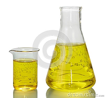 A chemical flask, a beaker with yellow liquids and a sheet of pa Stock Photo