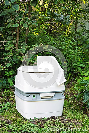Chemical portable toilet. Single portable toilet standing on green nature courtyard background Stock Photo