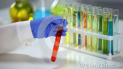 Chemist checking tube with orange liquid, dyestuff agent, washing substance Stock Photo