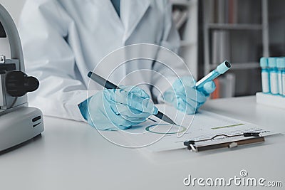 Chemist taking notes on research data, Scientist is working in the laboratory, Chemist is analyzing experimental results and Stock Photo