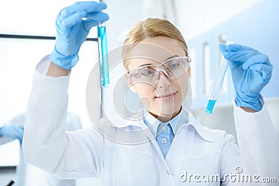 Chemist in white coat holding test tubes with reagents and making experiment Stock Photo