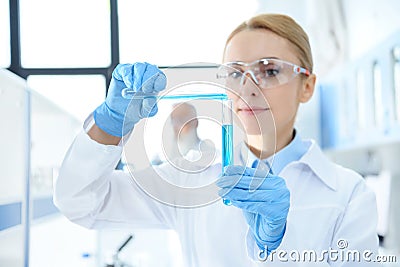 Chemist in white coat holding test tubes with reagents and making experiment Stock Photo