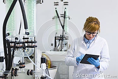 Chemist working on tablet next to rotavapor machine in laboratory Stock Photo