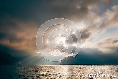 Cheow Lan Lake in the early morning under sunrise rays struggle through the storm clouds , Khao Sok national park, Thailand Stock Photo
