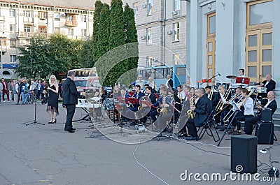 Brass band accompanies singer building outdoors. Editorial Stock Photo