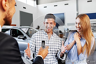 Cherrful young couple at the dealership buying a new car Stock Photo