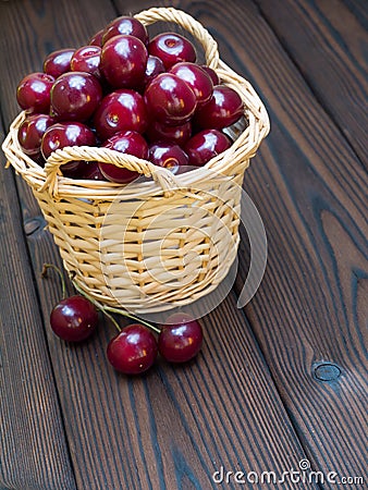 Cherries in the basket on the dark textured wooden planks Stock Photo