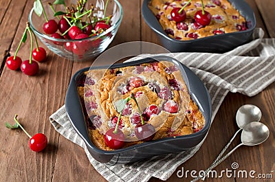 Cherry clafouti in portional ceramic forms on rustic wooden background Stock Photo