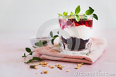 Cherry, cream cheese and chocolate biscuit portion layered dessert in glass, pink background. Black forest trifle. Summer dessert Stock Photo