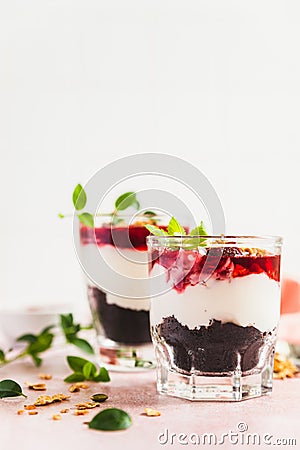 Cherry, cream cheese and chocolate biscuit portion layered dessert in glass, pink background. Black forest trifle. Summer dessert Stock Photo