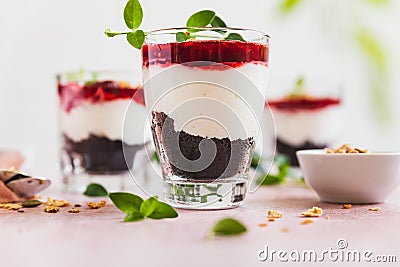 Cherry, cream cheese and chocolate biscuit portion layered dessert in glass, pink background. Black forest trifle. Summer dessert Stock Photo