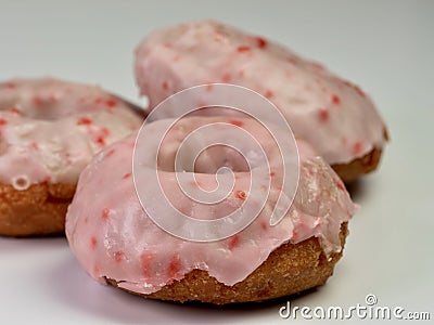 Cherry donuts with pink icing glaze piled up and ready to eat. Up close still life photography shot of 3 donuts Stock Photo