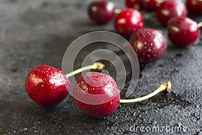 Cherry with drops of water on a black wet surface Stock Photo