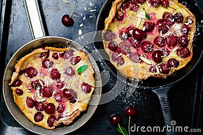 Cherry Dutch Baby, Puff German Pancake on Vintage Pans and Dark Background, Homemade Summer Dessert Stock Photo