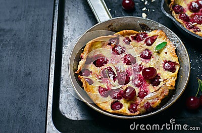 Cherry Dutch Baby, Puff German Pancake on Vintage Pans and Dark Background, Homemade Summer Dessert Stock Photo