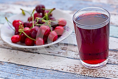 Cherry juice with cherries in plate on turquoise table Stock Photo