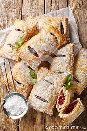 Cherry puff pastry with powdered sugar and mint close-up. Vertical top view Stock Photo