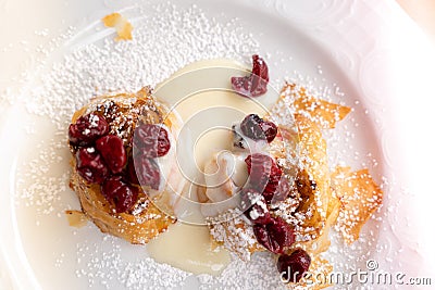 Cherry puff pastry strudel served on a white plate with vanilla cream sauce and sugar powder Stock Photo