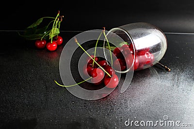 Cherry red ripe berry fell out of the glass on a black background with the est for the text. vitamins seasonal berry hemoglobin Stock Photo