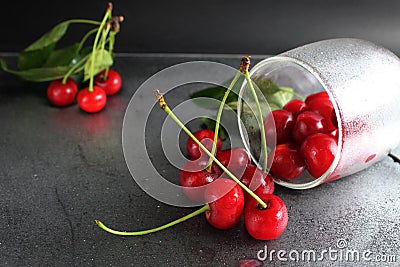 Cherry red ripe berry fell out of the glass on a black background with the est for the text. vitamins seasonal berry hemoglobin Stock Photo