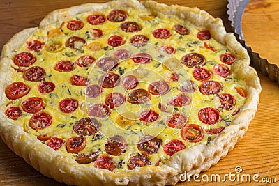 Cherry tomato tart horizontal image of puff pastry tomato cheese and egg quiche out of oven on wooden table Stock Photo