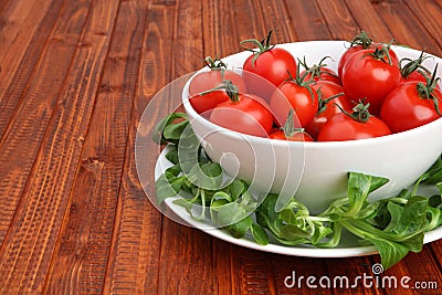 Cherry tomatoes in a bowl surrounded by green mache lettuce Stock Photo
