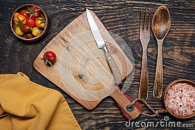 cherry tomatoes, knife and cutting board on a dark wooden table. View from above. Space for text Stock Photo