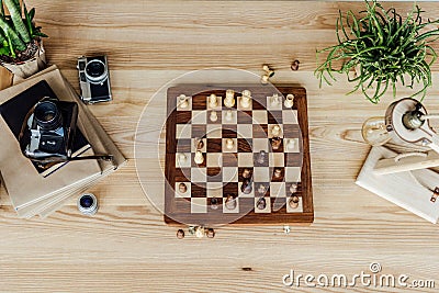 Chess board set with old vintage cameras and books on wooden table Stock Photo