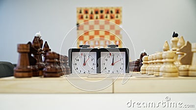 A chess clock is standing next to a chessboard waiting for the start of the game Stock Photo