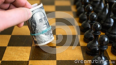 Chess game and rolled dollar bills as white move Stock Photo