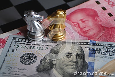 Chess game, two knights face to face on Chinese yuan and US dollar background. Trade way concept. Conflict between two big Stock Photo