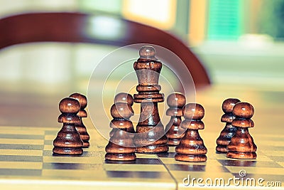 Chess pawns around chess king on table. Chess game, strategy. Stock Photo