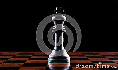 chess piece of a black king on a chessboard on a black background Stock Photo