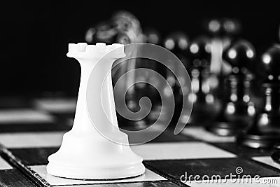 Chess pieces, a white rook on a chessboard, against a row of black pieces. The concept of career, competition, startup. Stock Photo